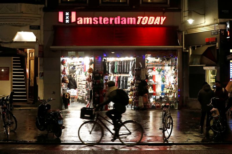 FILE PHOTO: A tourist poses for a photo near a canal in the red district of Amsterdam